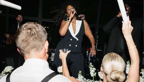Bride and groom cheering in front of the stage as a Lost Wax vocalist sings at Erin + Mat's wedding at Avent Orangery in Kansas City, KS on May 1, 2026